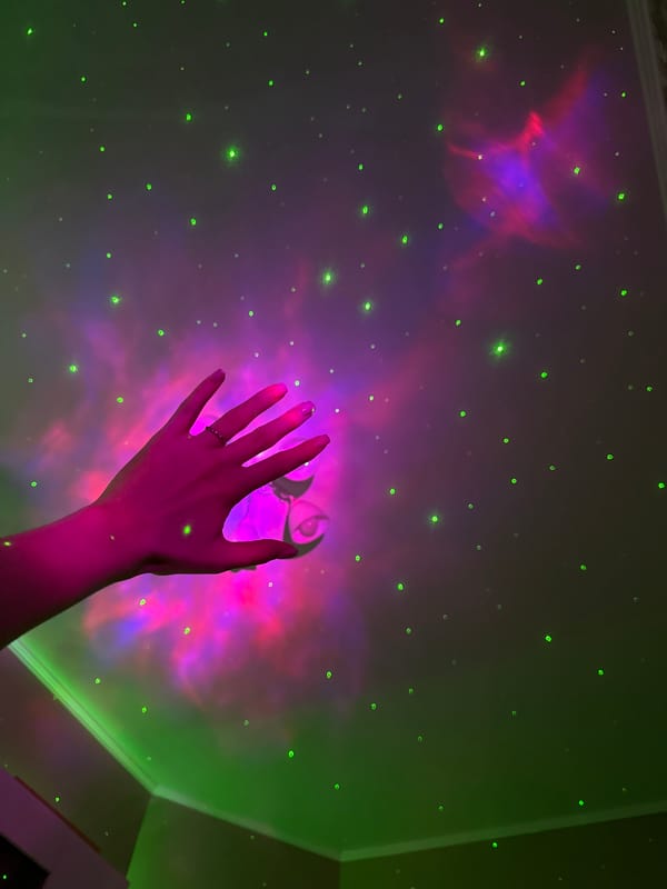 Cozy bedroom setup with galaxy projector, moon lamp, and skincare