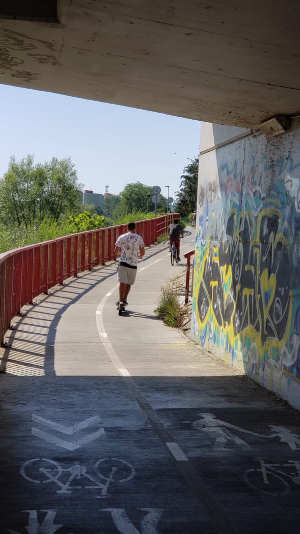 Graffiti-covered bridge frames a bike path along the Torysa River