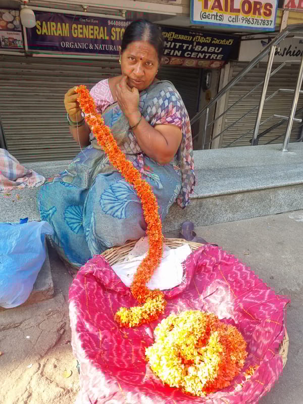 Woman creates flower garlands from marigolds in Puttaparthi