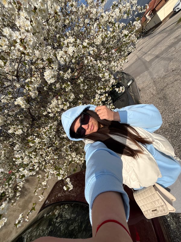 Woman photographs spring blossoms by car in Karlovo, Bulgaria