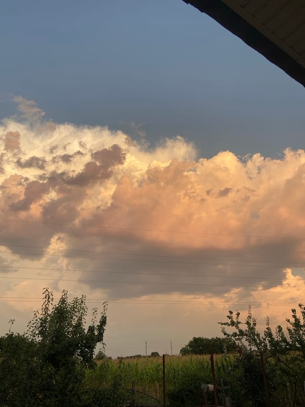 Rural sunset sky, clouds, and a parked car near a fence