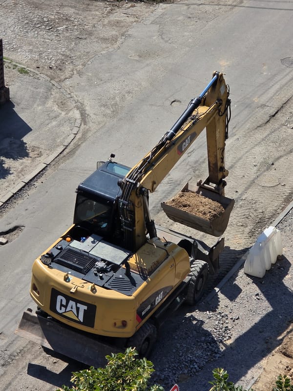Excavator at work near a tree-lined residential area