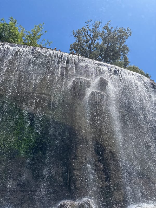 Waterfall observed at rocky cliff face with clear skies