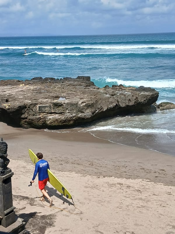Surfers and beachgoers on an Indonesian beach on a clear day