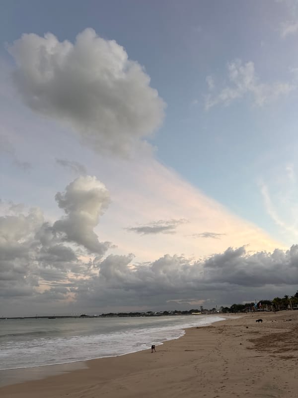 Kuta Beach at golden hour — waves, clouds, and people.