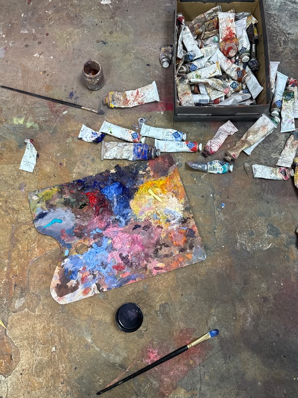 Artist's studio workspace documented with paintings and scattered supplies
