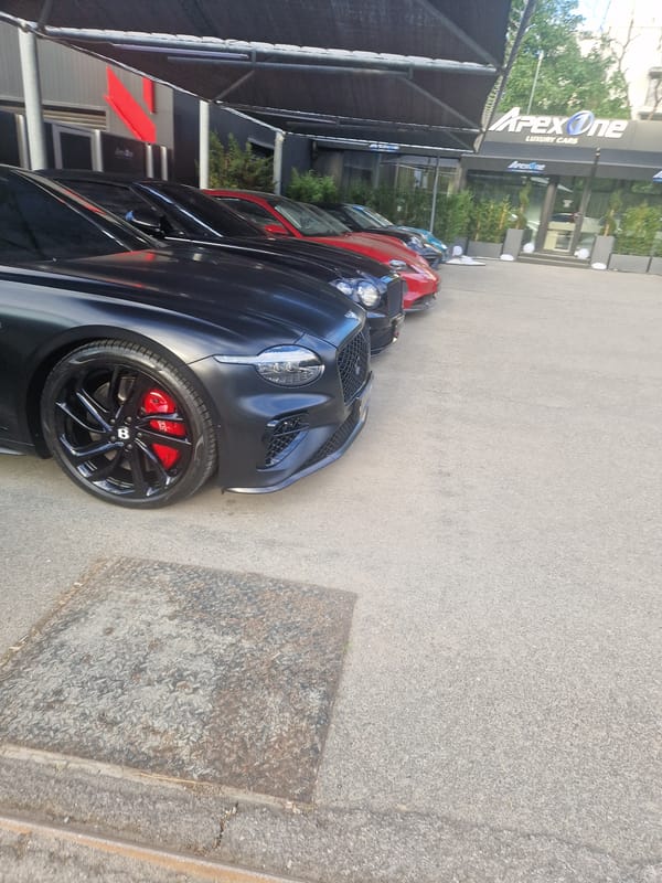 Person visits luxury car dealership, photographed outdoors