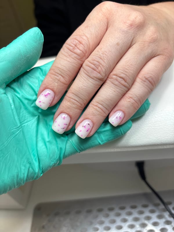 Gloved hand holds manicured hand with floral nail art