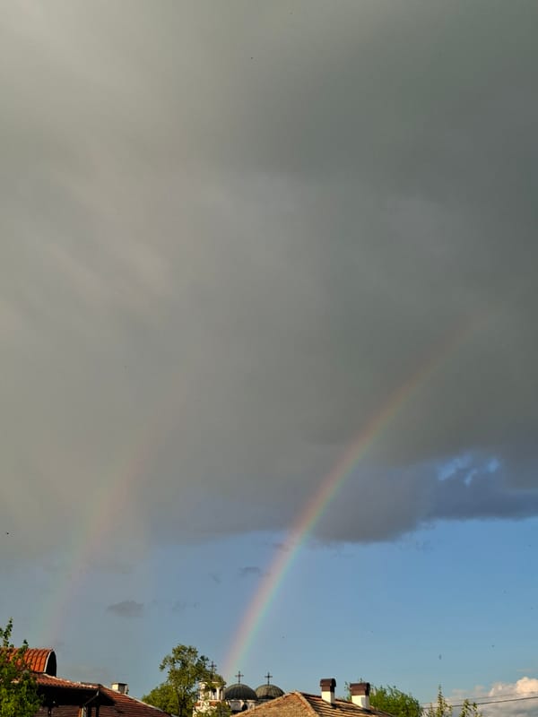 Rainbow appears over domed buildings during afternoon sky clearing