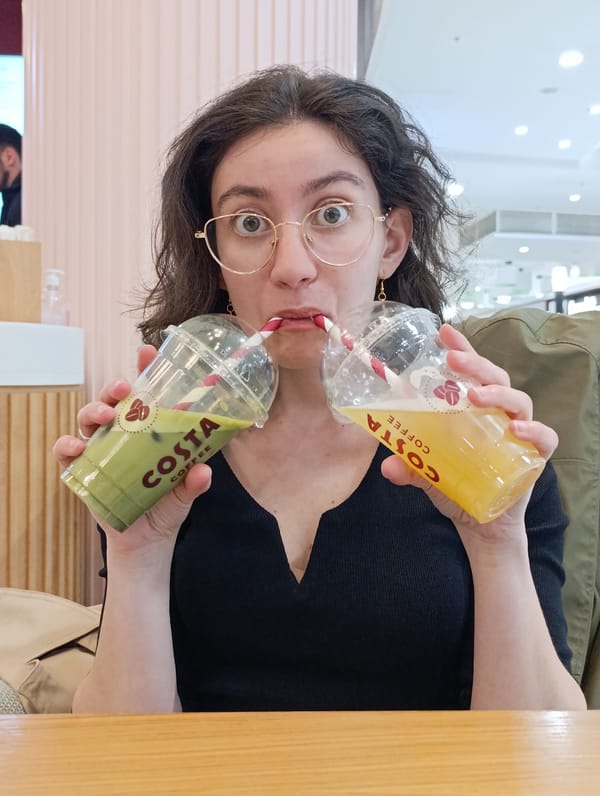 Woman playfully drinks from two Costa Coffee cups in Sofia