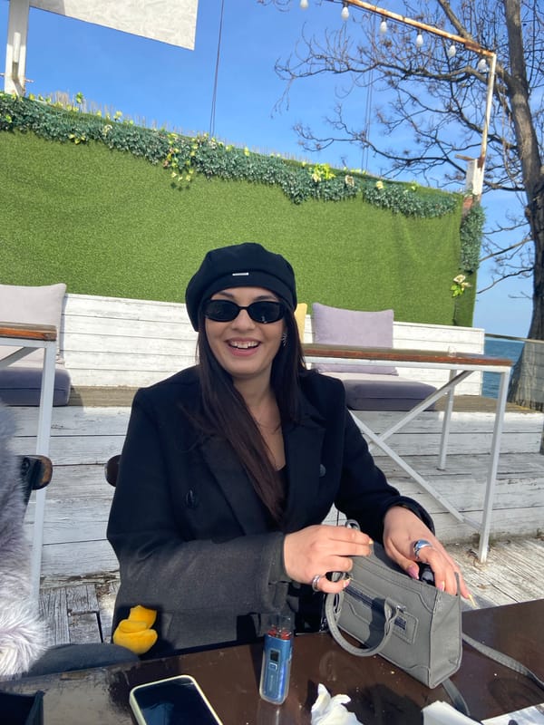 Woman in beret photographed smiling at outdoor table