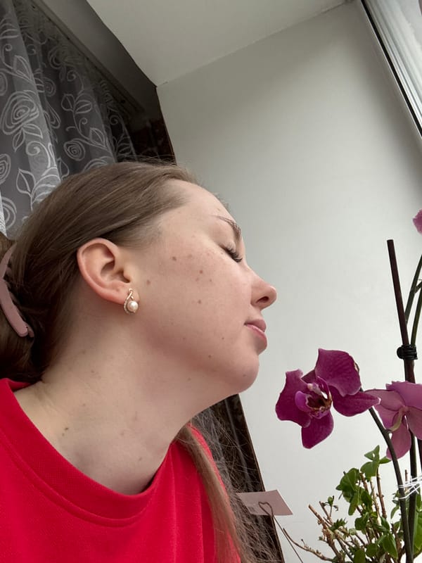 Woman photographed with purple orchid in indoor setting