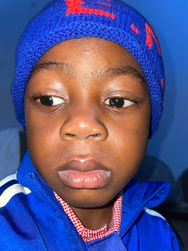 Child in blue tracksuit rests on furniture in Jos