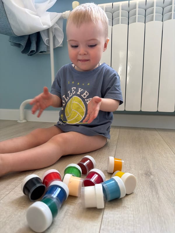 Child plays with paint containers on floor in Votkinsk