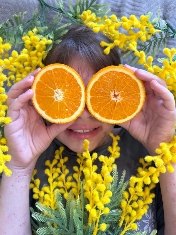 Person playfully poses with orange halves over eyes