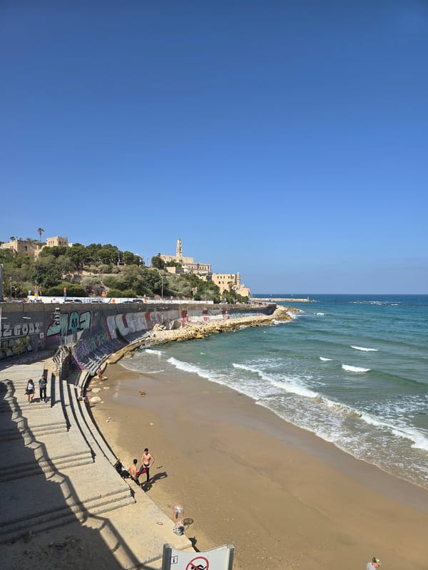 Morning beachgoers walk Tel Aviv shoreline at sunrise