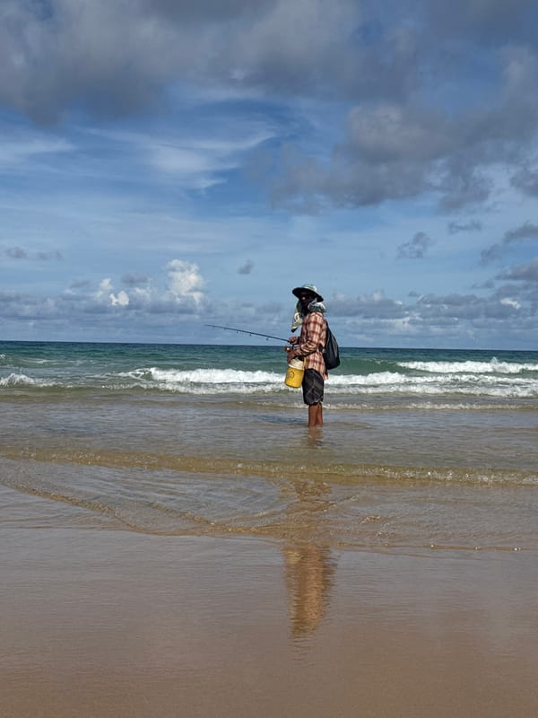 Dogs, flags, and a fisherman statue on Karon Beach