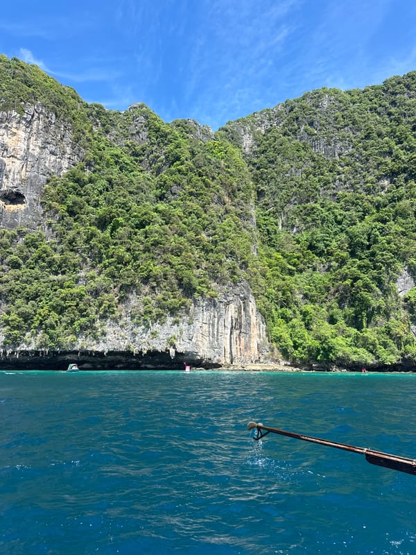 Longtail boat navigates limestone karsts off Haad Yao