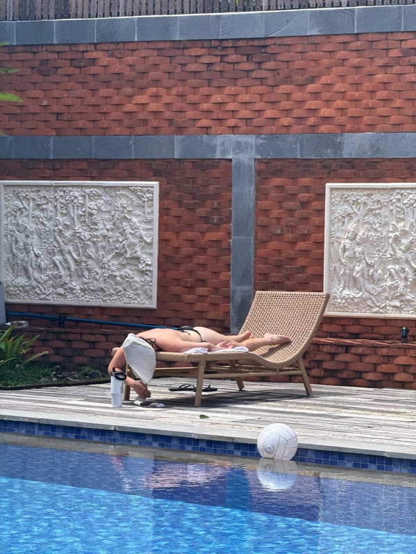 Woman sunbathes poolside in early morning North Kuta