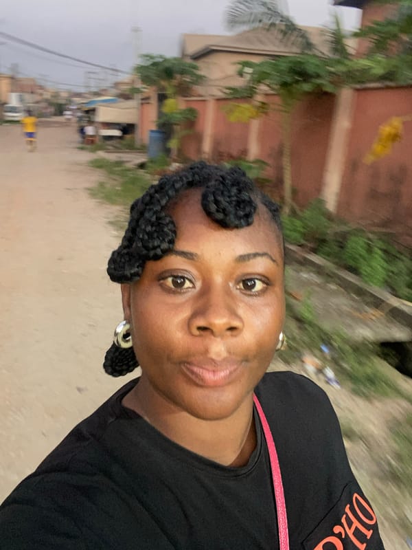 Woman takes selfie on unpaved Lagos street at dusk