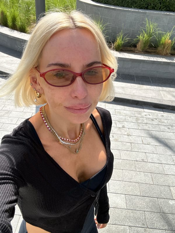 Woman takes outdoor selfie in Dubai wearing red sunglasses
