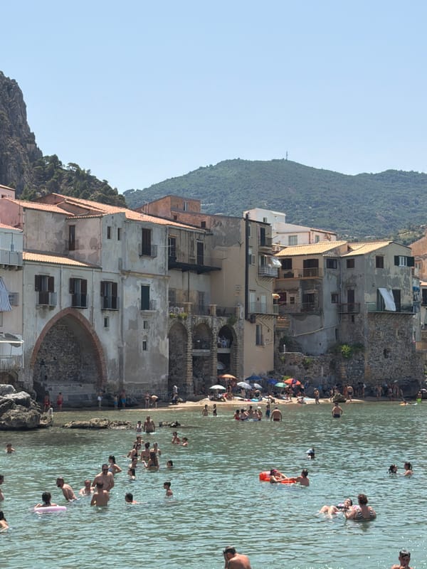 Cefalù beach in full summer swing, umbrellas and medieval backdrop