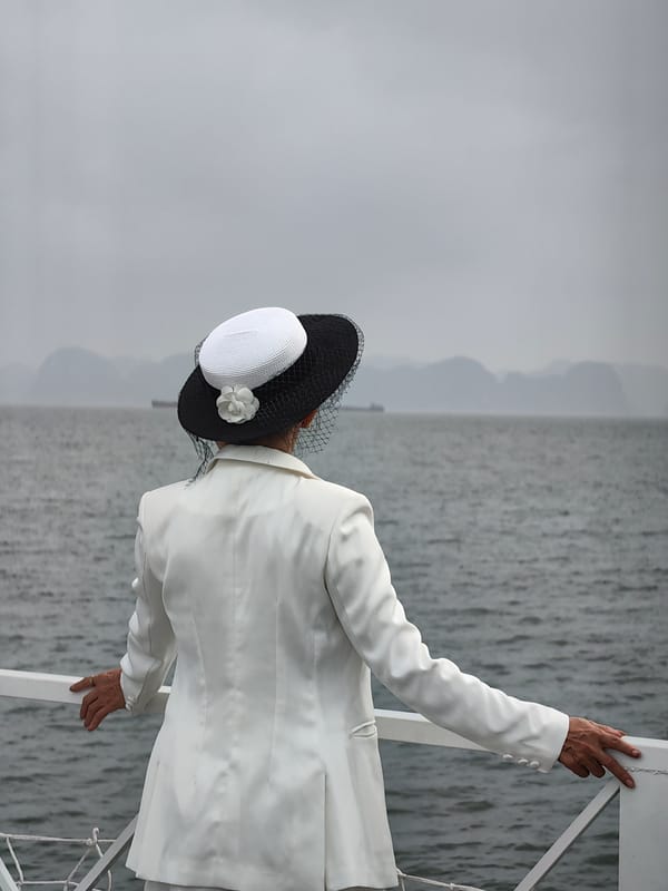 Woman in white contemplates water view from boat deck