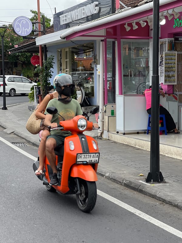 Morning scooter traffic flows past Icon Bali mall in Denpasar