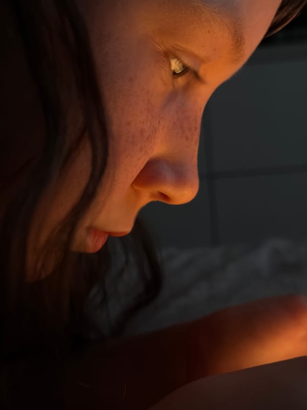 Child rests with phone in darkened room in Markovo