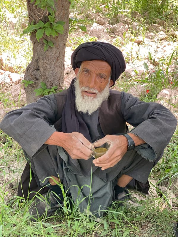 Elderly man in traditional dress sits outdoors in Nowruzi