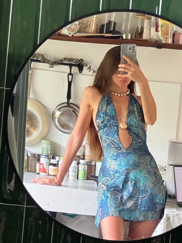 Woman takes mirror selfies in patterned dress indoors