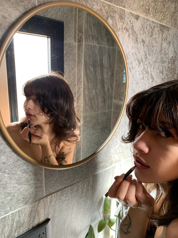 Woman applies makeup in mirror in Buenos Aires