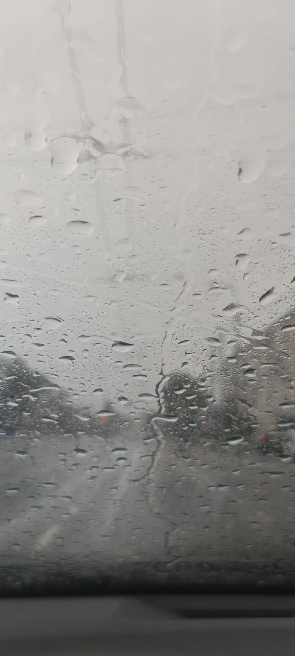 Rain-soaked city streets seen through a wet windshield