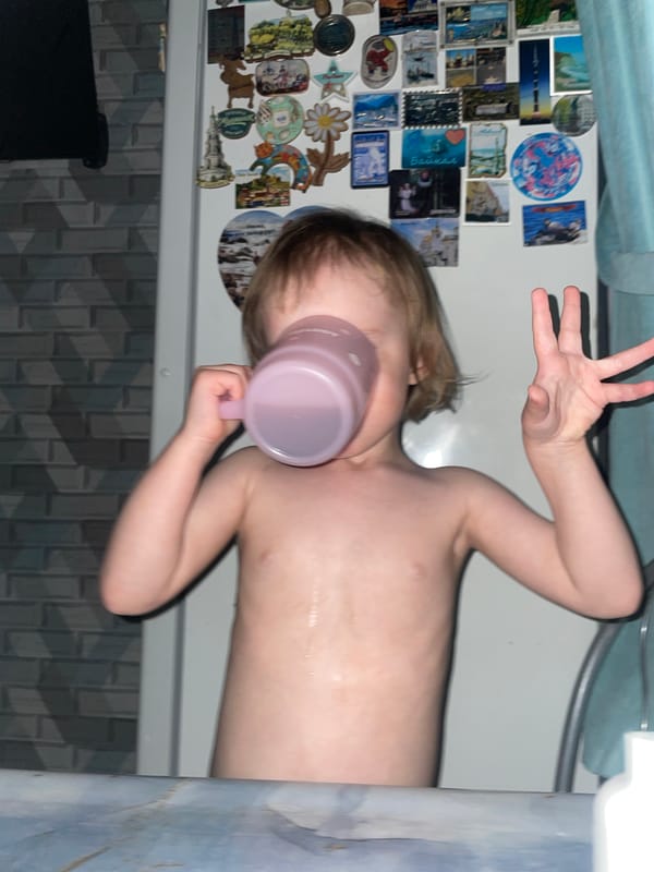 Child drinks from pink cup during bath time in Vladivostok