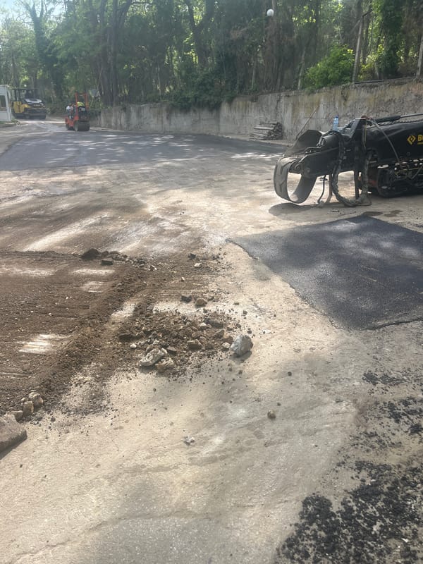 Urban street repair crews operate heavy equipment during asphalt work