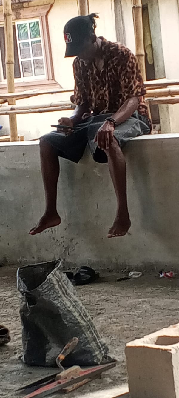 Person in leopard print shirt sits on ledge with phone