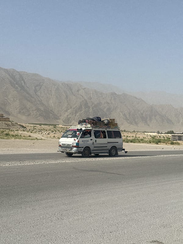 Loaded passenger van travels through arid Pakistani landscape