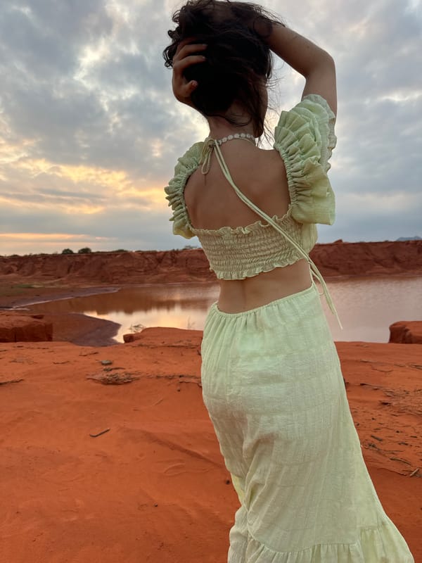Woman in green visits red rock formation in Mui Ne