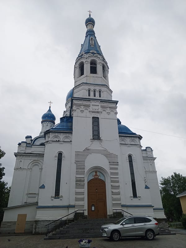 White church with blue domes and gold stars, low-angle view