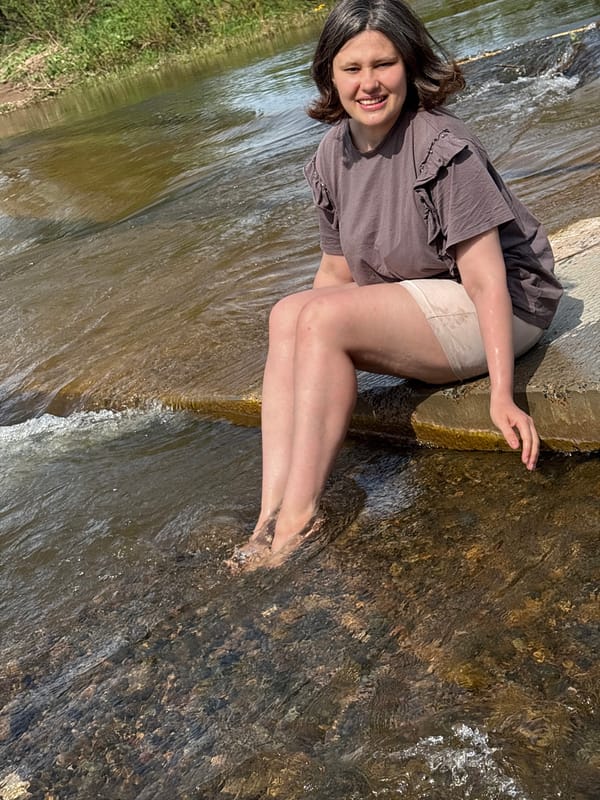 Woman sits by stream waterfall in Russian village