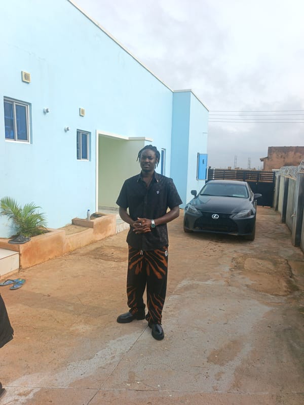 Paved driveway pause outside a light blue building, Nigeria