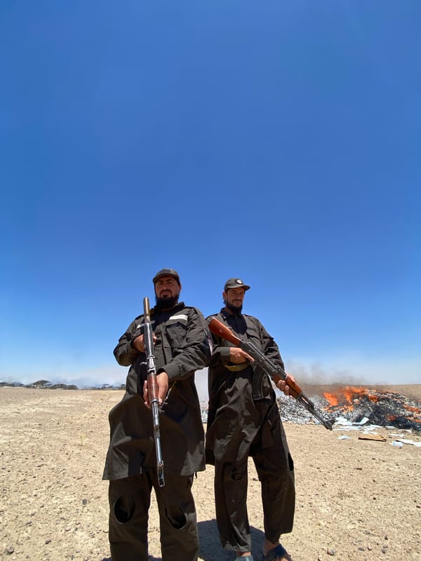 Armed figures stand near burning debris in Mandisar, Afghanistan