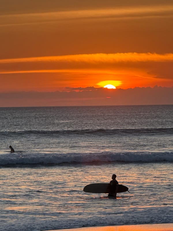Surfer paddles at sunset in Kuta waters