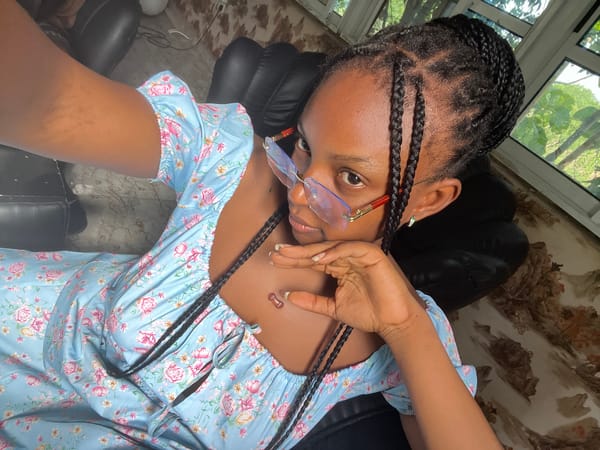 Woman in floral dress relaxes in chair, Adankolo