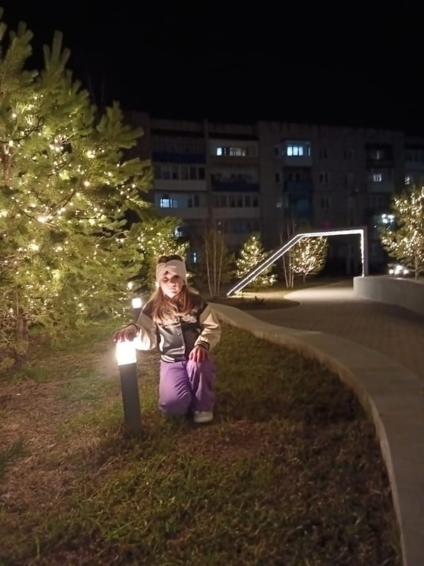 Woman poses in illuminated park during evening in Osa