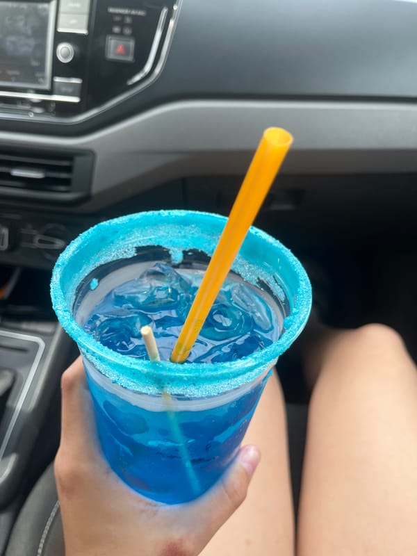 Person enjoys blue beverage in car in Cholula