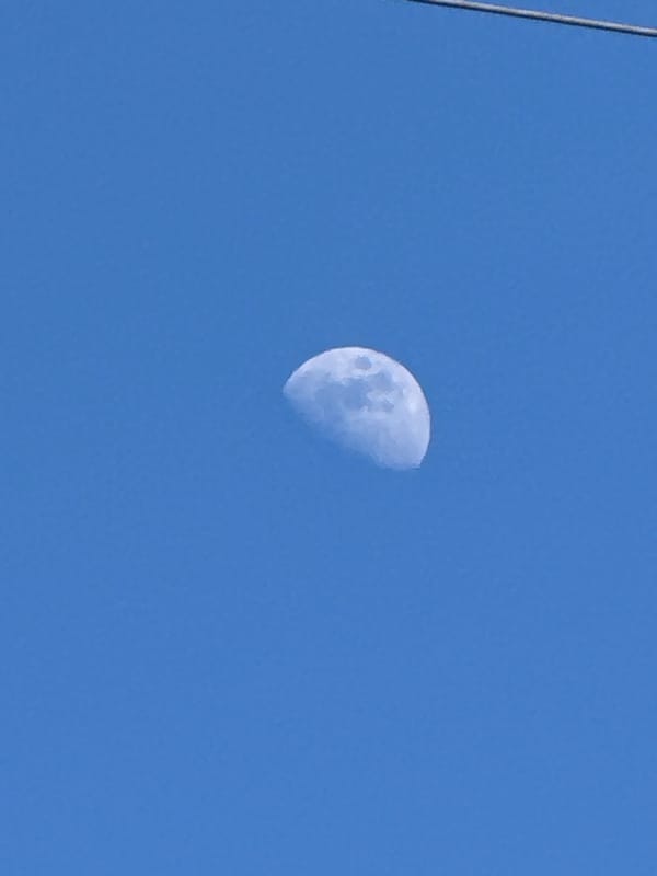 Half-moon visible in clear daylight sky over French commune