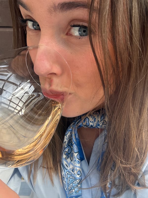 Woman drinks beverage while dog rests nearby in Lommedalen