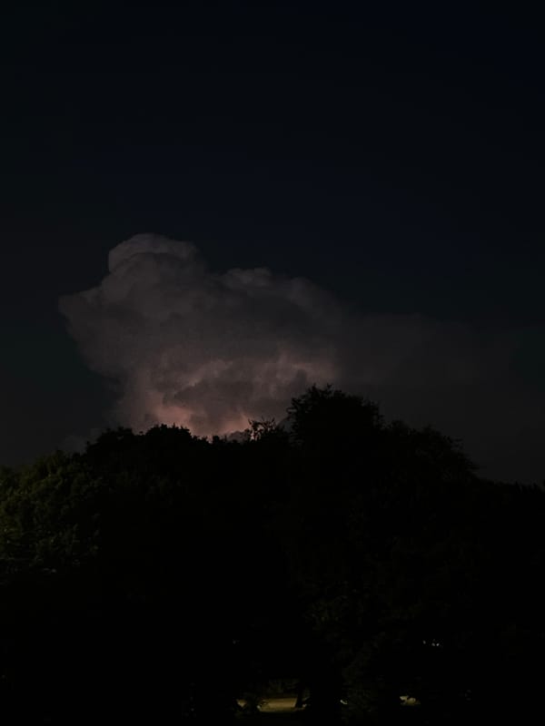Storm cloud glows over Milan's night skyline