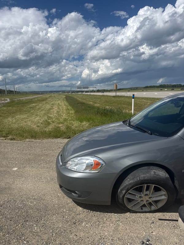 Grey sedan pulled over on Calgary highway with flat tire